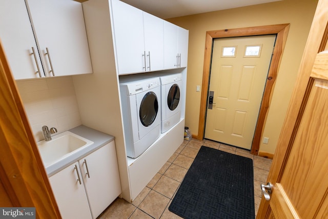 washroom with light tile patterned flooring, cabinet space, independent washer and dryer, and a sink