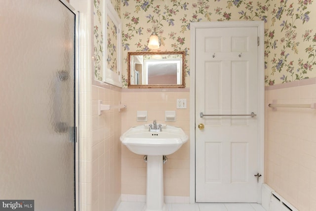 bathroom with wallpapered walls, baseboard heating, wainscoting, a stall shower, and tile walls