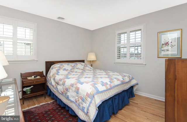 bedroom with wood finished floors, visible vents, and baseboards