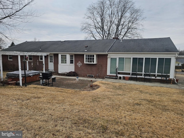 rear view of property featuring entry steps, brick siding, a lawn, and a hot tub