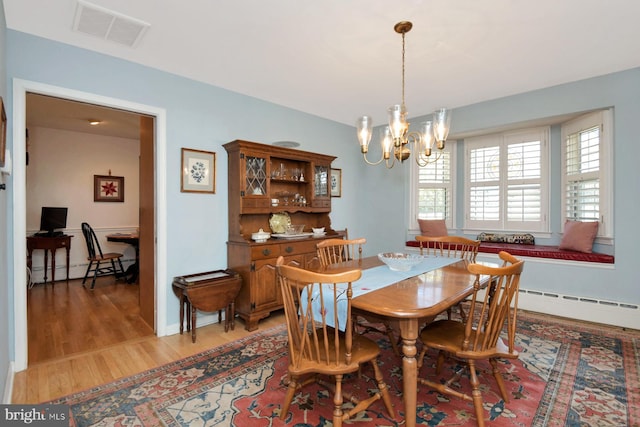 dining space with visible vents, baseboard heating, light wood-style flooring, a notable chandelier, and a baseboard radiator