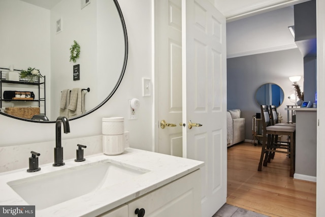 bathroom with visible vents, vanity, crown molding, and wood finished floors