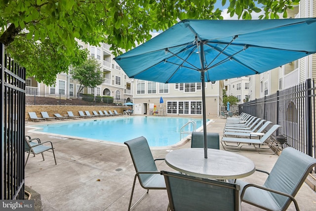 community pool with fence and a patio area