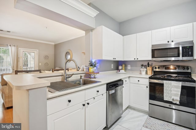 kitchen featuring a peninsula, ornamental molding, light countertops, white cabinets, and appliances with stainless steel finishes