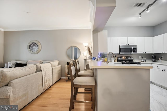 kitchen featuring open floor plan, appliances with stainless steel finishes, a kitchen bar, and visible vents