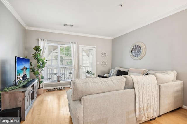 living room featuring visible vents, light wood finished floors, and ornamental molding