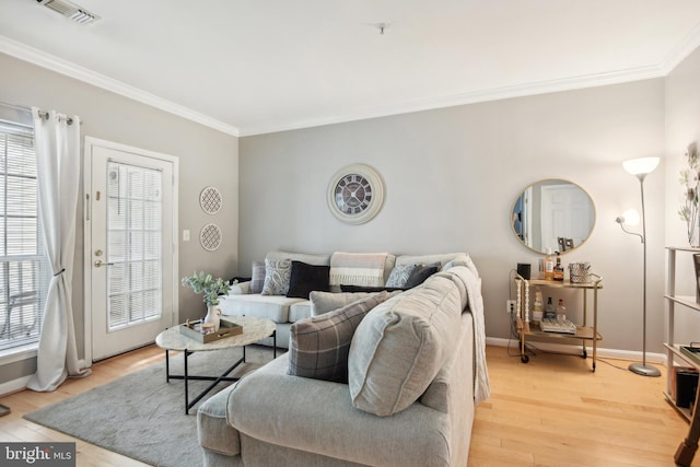 living area featuring visible vents, baseboards, light wood-style flooring, and crown molding