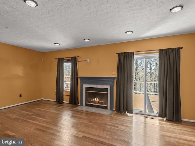 unfurnished living room featuring plenty of natural light, a fireplace with flush hearth, and hardwood / wood-style flooring