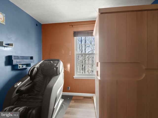 laundry room with a textured ceiling, wood finished floors, and baseboards