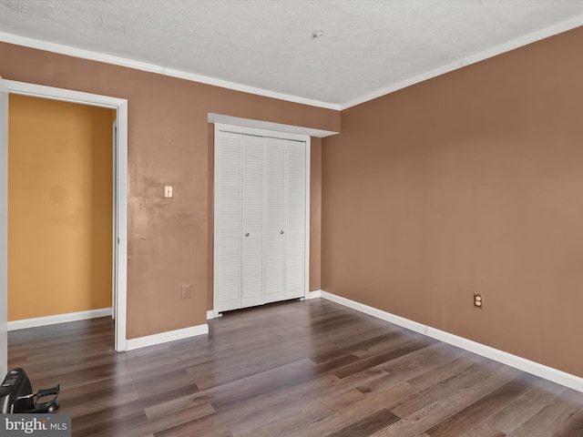 unfurnished bedroom with a closet, ornamental molding, a textured ceiling, wood finished floors, and baseboards