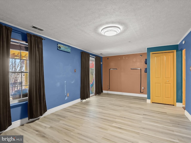 spare room with a healthy amount of sunlight, visible vents, baseboards, and wood finished floors