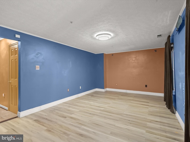 unfurnished room with baseboards, visible vents, a textured ceiling, and light wood finished floors