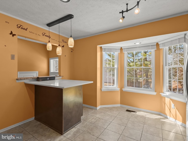 kitchen featuring hanging light fixtures, visible vents, a textured ceiling, and light tile patterned flooring