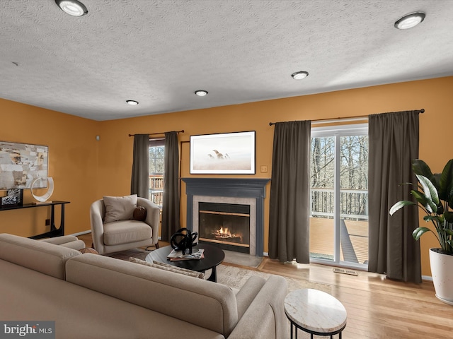 living room with a textured ceiling, a fireplace, wood finished floors, and a wealth of natural light