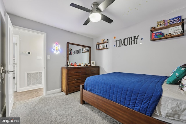 bedroom featuring baseboards, visible vents, a ceiling fan, and light colored carpet