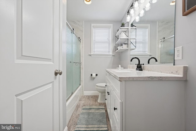 full bath with baseboards, toilet, shower / bath combination with glass door, vanity, and wood finish floors