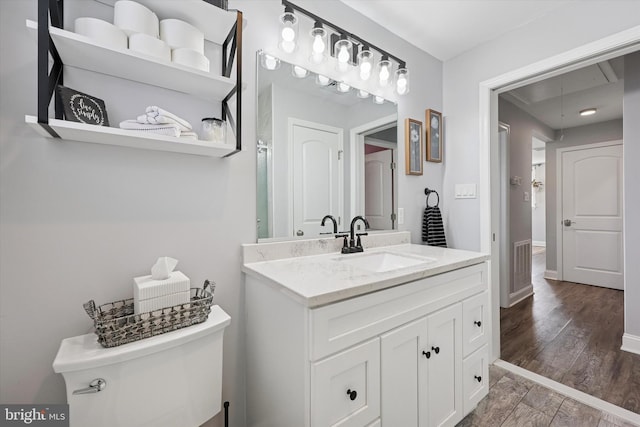 bathroom with toilet, baseboards, wood finished floors, and vanity