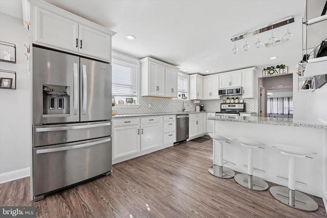 kitchen with stainless steel appliances, tasteful backsplash, dark wood-style flooring, and white cabinetry