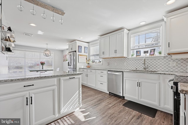 kitchen featuring stainless steel appliances, light wood-type flooring, a sink, and white cabinetry