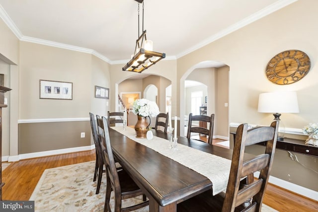 dining area featuring wood finished floors, arched walkways, and baseboards