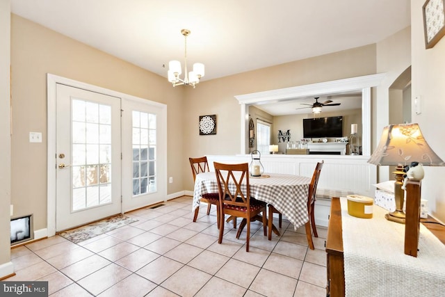 dining area featuring visible vents, a healthy amount of sunlight, a fireplace, and ceiling fan with notable chandelier