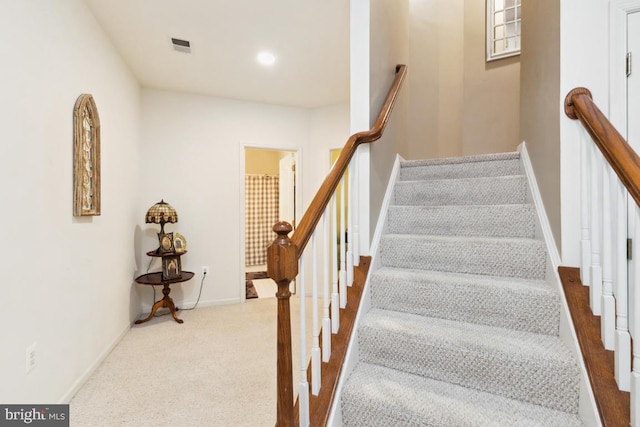 staircase with visible vents, baseboards, and carpet flooring