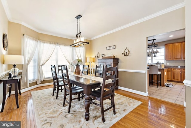 dining space featuring light wood-type flooring, an inviting chandelier, and ornamental molding