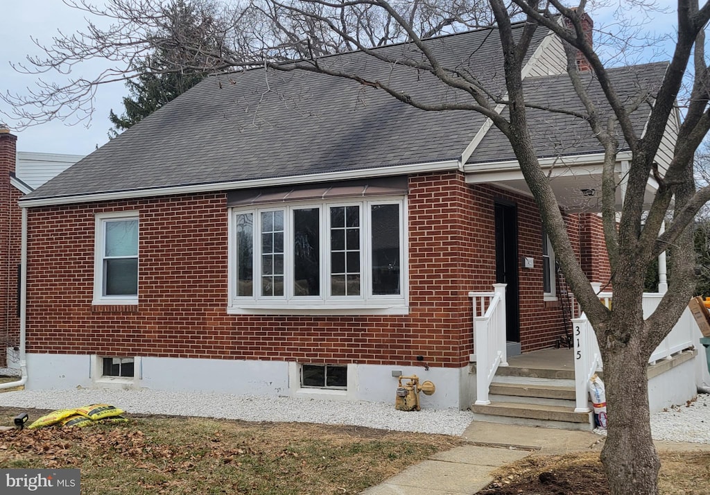 view of home's exterior with brick siding and a shingled roof