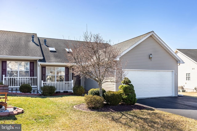 view of front of house with roof with shingles, covered porch, a front lawn, a garage, and aphalt driveway