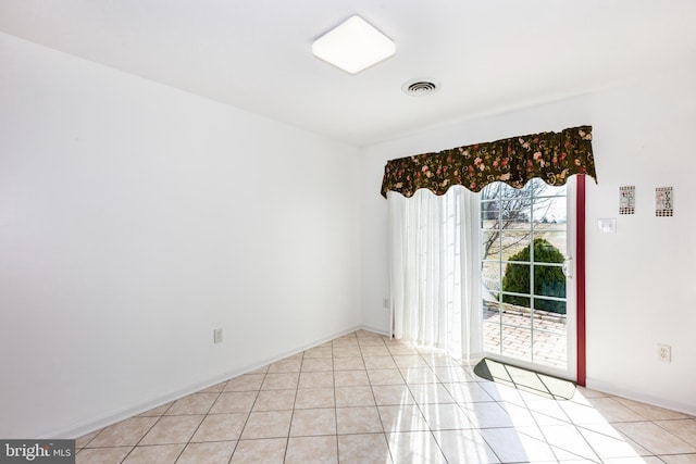 empty room with light tile patterned floors, visible vents, and baseboards