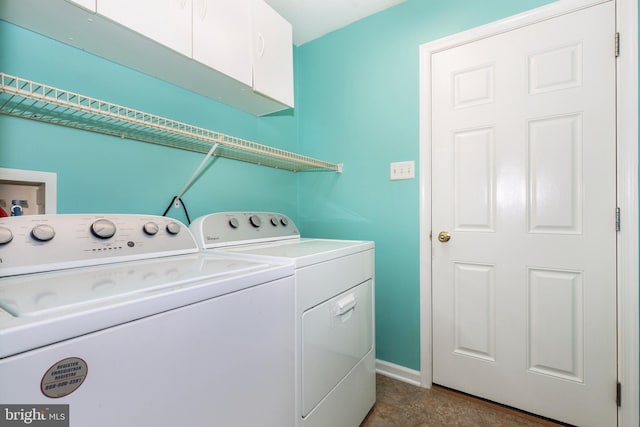 clothes washing area with washer and clothes dryer, cabinet space, and baseboards