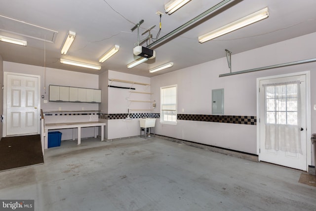 garage with electric panel, a garage door opener, and a sink