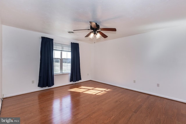 unfurnished room featuring a ceiling fan, wood finished floors, visible vents, and baseboards