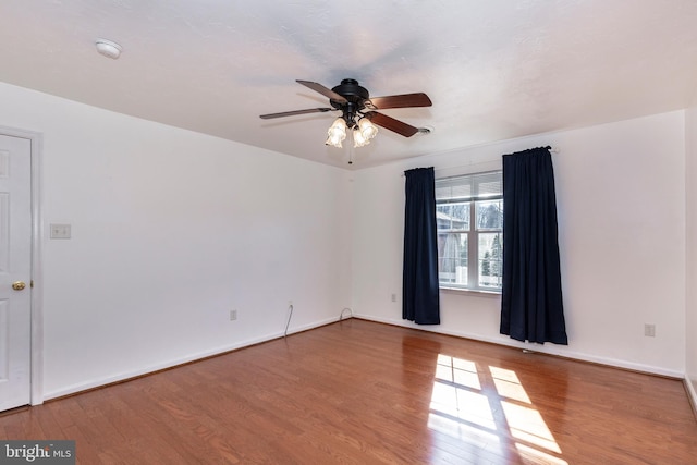 spare room with wood finished floors, baseboards, and ceiling fan