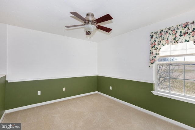 carpeted empty room with a ceiling fan and baseboards