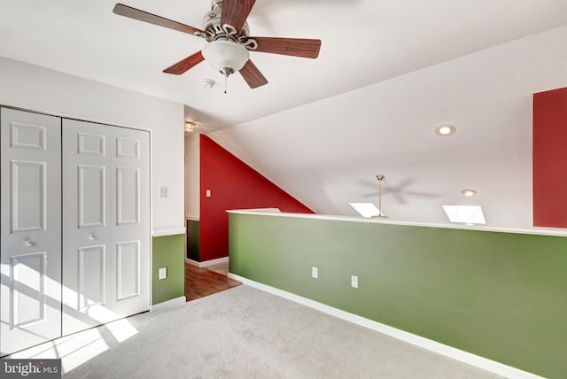 interior space featuring carpet, baseboards, ceiling fan, vaulted ceiling, and a closet