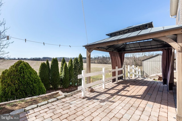 view of patio featuring a gazebo, a rural view, and fence