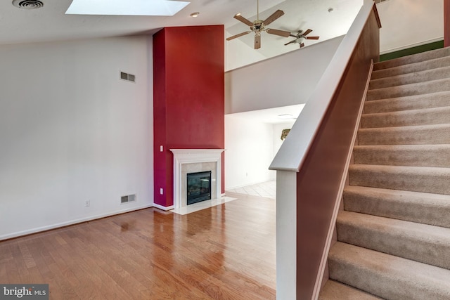 stairs featuring a skylight, wood finished floors, and visible vents