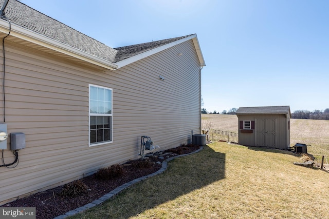 view of side of home featuring a shingled roof, fence, a yard, an outbuilding, and a storage unit