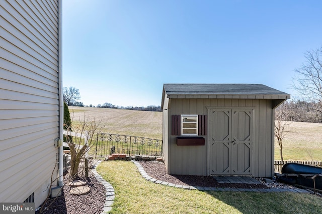 view of shed with a rural view and fence