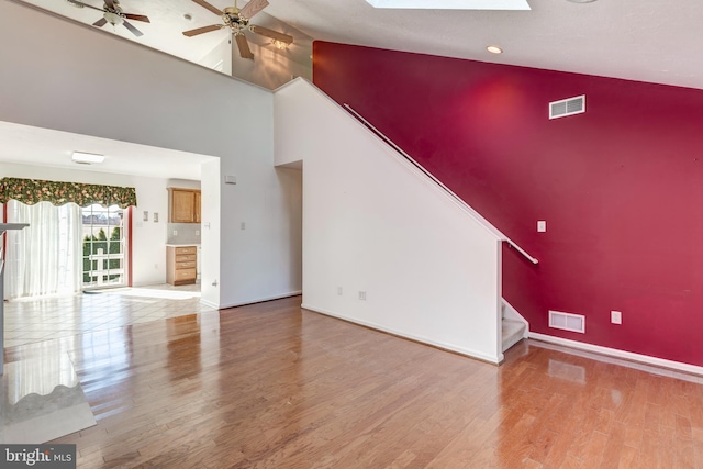 unfurnished living room with visible vents, wood finished floors, a skylight, and stairway