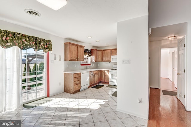 kitchen featuring visible vents, backsplash, light countertops, light tile patterned floors, and white appliances