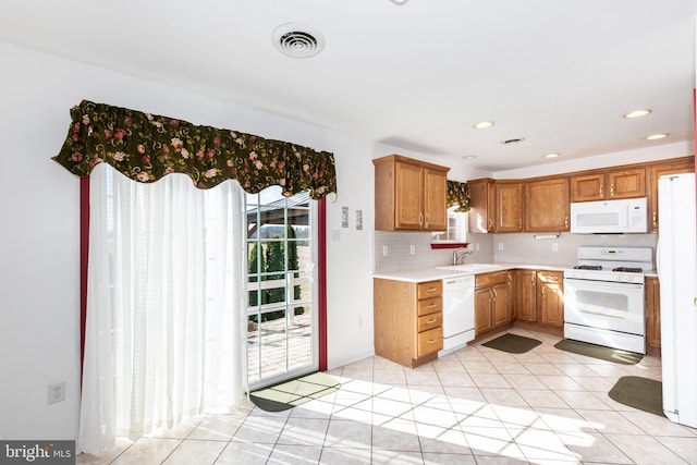 kitchen with white appliances, visible vents, a sink, light countertops, and backsplash