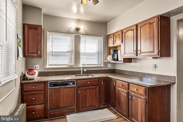 kitchen with dark countertops, paneled dishwasher, radiator heating unit, and a sink