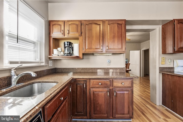 kitchen featuring light wood-type flooring, a sink, dark stone countertops, and open shelves