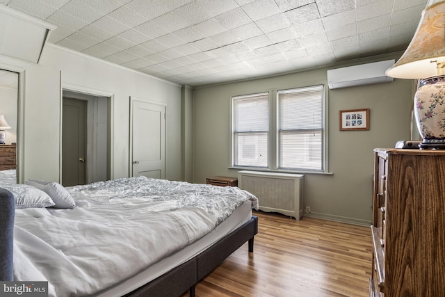 bedroom with baseboards, a wall unit AC, radiator heating unit, ornamental molding, and wood finished floors