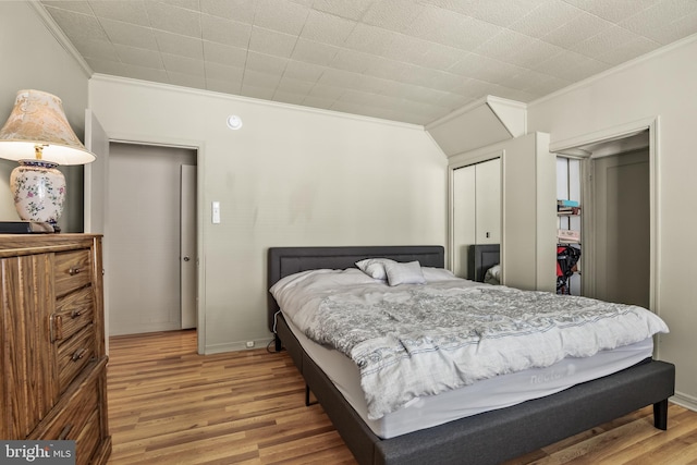 bedroom with baseboards, a closet, wood finished floors, and crown molding