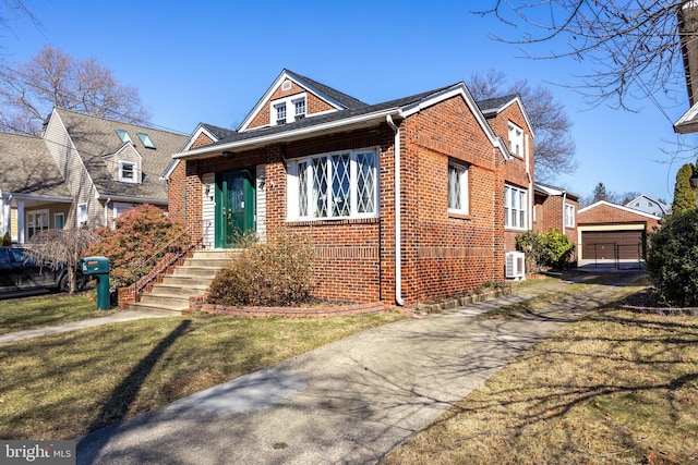 bungalow featuring a front yard, an outbuilding, a detached garage, and brick siding