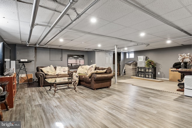 living room with a drop ceiling, baseboards, and wood finished floors