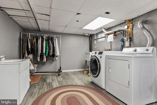 clothes washing area with concrete block wall, laundry area, light wood finished floors, washer and dryer, and a sink